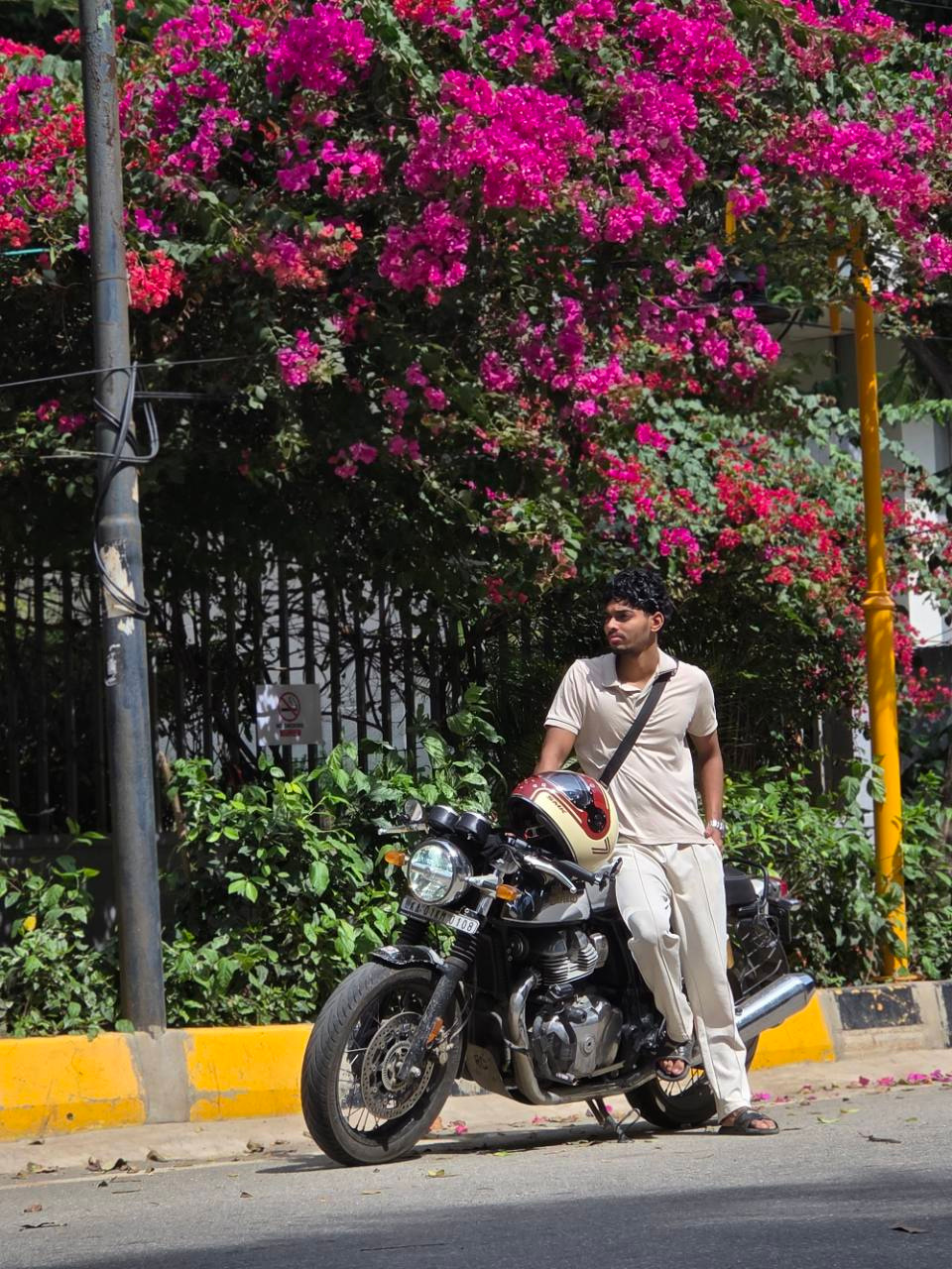 Ranga beside his motorbike under pink flowers